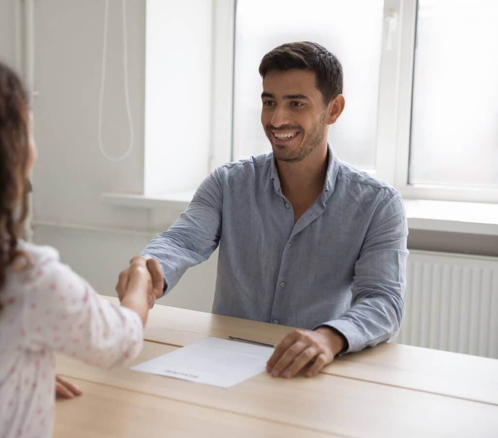 Businessman shake hands female applicant sit at desk during successful job interview.
